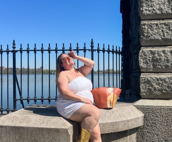 Sarah wearing a white plus size linen romper in front of a Central Park reservoir