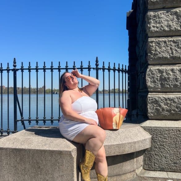 Sarah wearing a white plus size linen romper in front of a Central Park reservoir