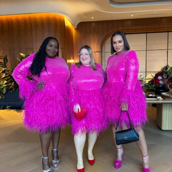 Sarah Chiwaya stands between fellow plus size style bloggers Alissa Wilson and Rochelle Johnson, all three wearing the pink sequined Kate Spade x Eloquii dress with feather trim